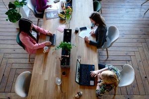 des femmes travaillant sur leur ordinateur portable autour d’une grande table dans un bureau